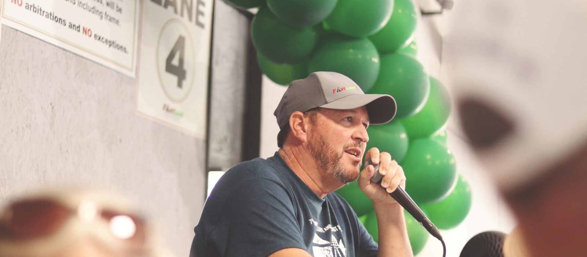 A Man Holding a Mike While Wearing A Baseball Cap